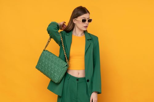 Khái niệm thời trang màu vàng và xanh lá cây với người phụ nữ trẻ sành điệu mặc vest và ví