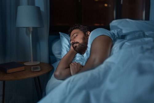 người đàn ông Ấn Độ ngủ trên giường ở nhà vào ban đêm