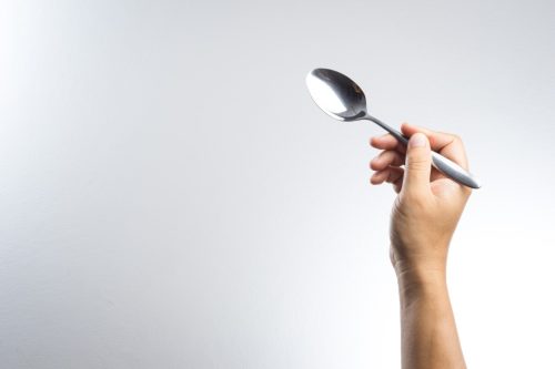 Man hand holding a silver spoon on white background