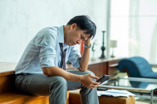 Depressed man employee have a bad new from smartphone and think of problem.