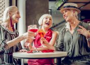 Three stylish senior women laughing and having drinks