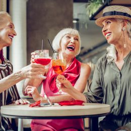 Three stylish senior women laughing and having drinks
