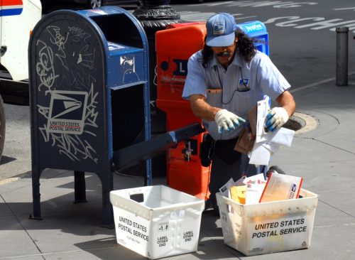 US postal service officer sorting mail on the streets of Manhattan on a sunny day in New York, United States