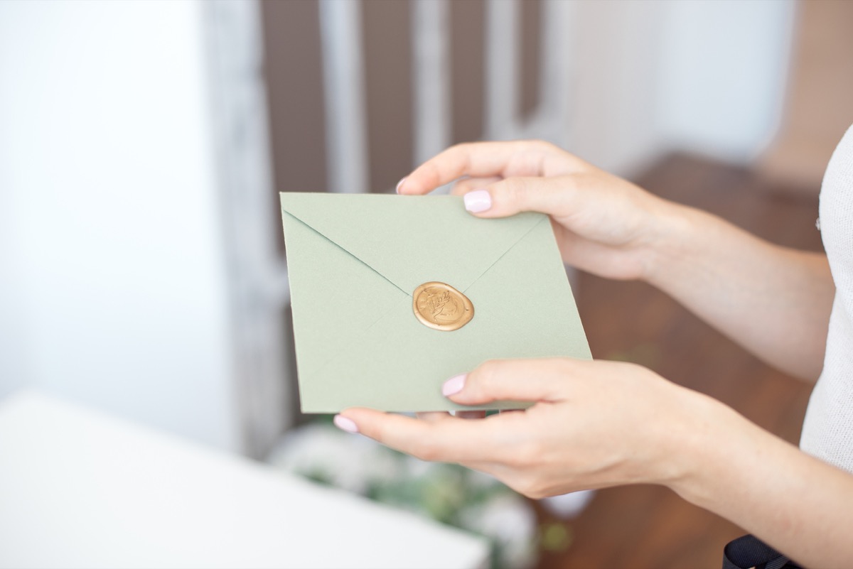 close up of female hands holding a green envelope
