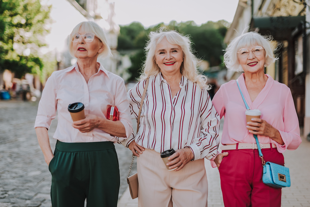 Waist up portrait of three beautiful older women having fun together while holding coffee