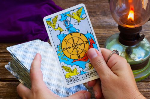 Person holding the Wheel of Fortune tarot card
