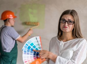 Frowning woman choosing color for painting walls in apartment