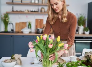 Caucasian,Woman,Putting,Vase,With,Fresh,Tulips,On,The,Table
