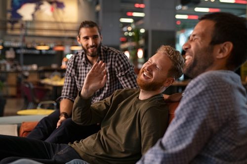 three men laughing and making yo mama jokes at a bar