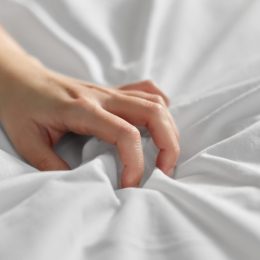 Woman's hand clutching bedsheets