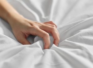 Woman's hand clutching bedsheets