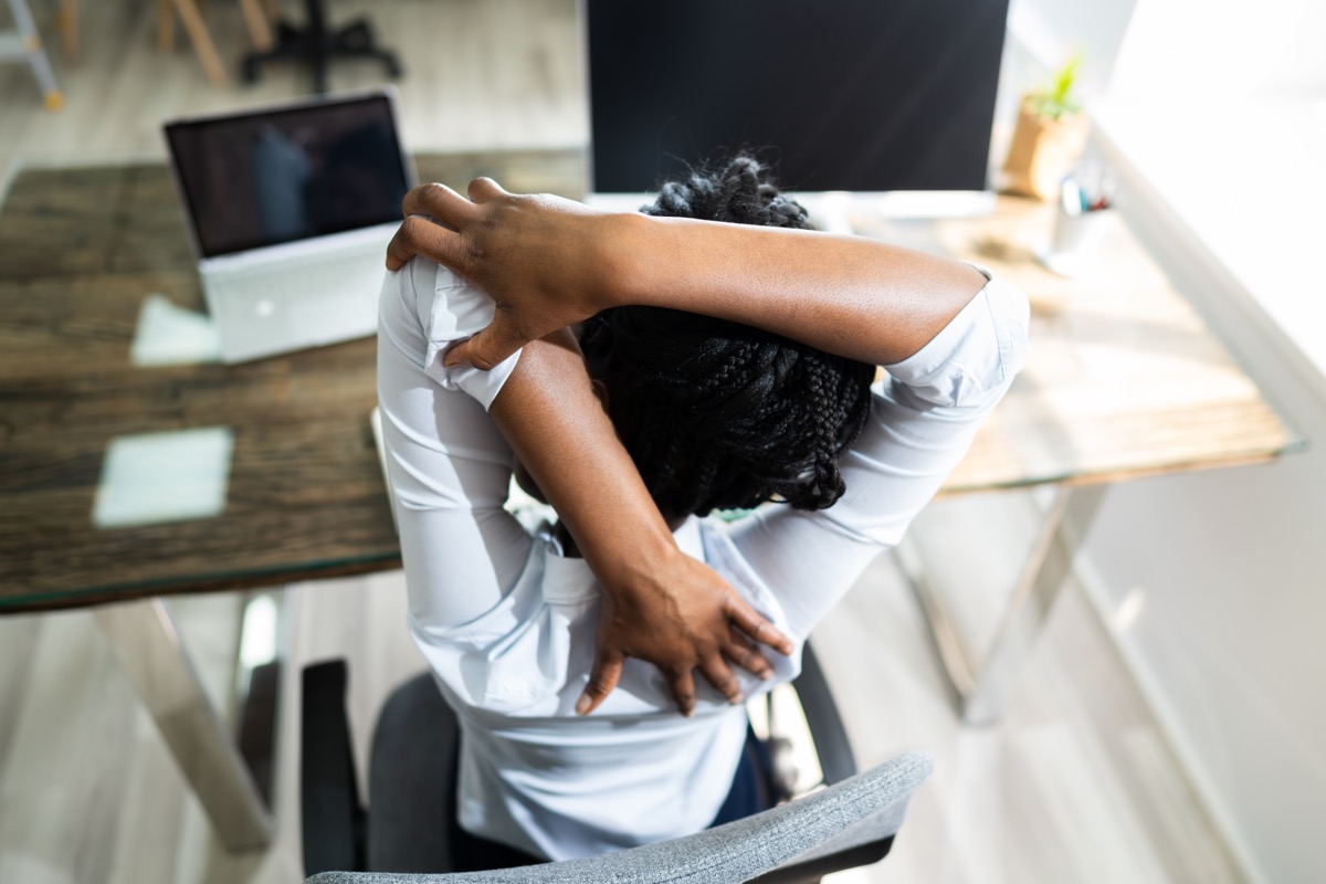 Black Woman Stretches In Office At Desk