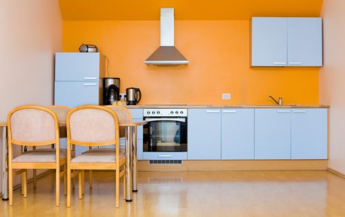 A contemporary kitchen with light blue cabinets and orange walls