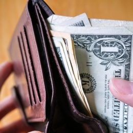 A close up of someone taking a dollar bill out of a wallet