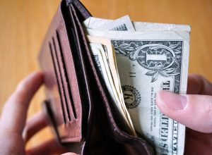 A close up of someone taking a dollar bill out of a wallet