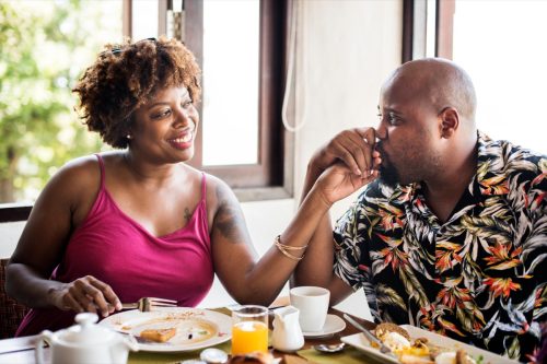 Man and woman eating brunch and holding hands