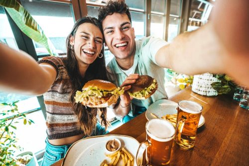couple taking a selfie while eating burgers at a diner