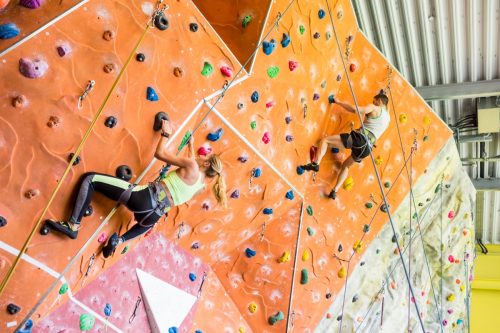 Fit couple rock climbing indoors at the gym