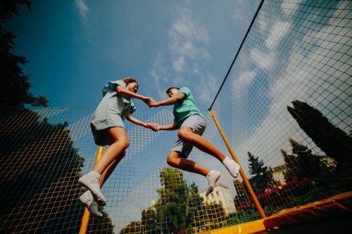 Man and woman bouncing on a trampoline while holding hands