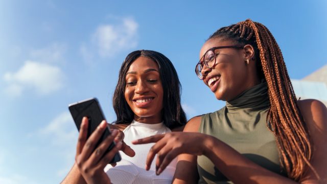 two women laughing at funny memes on their phone