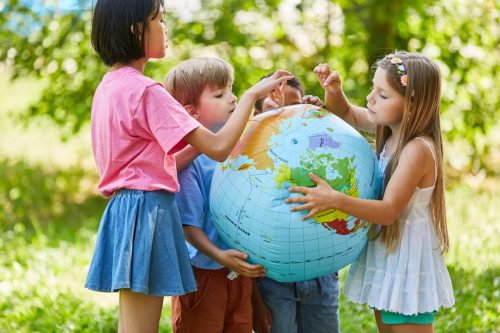 children standing around a globe learning trivia questions for kids