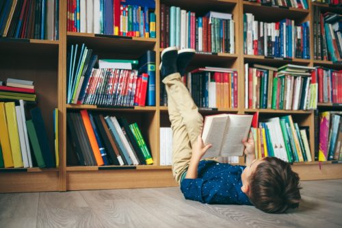 little boy laying on the floor reading a book