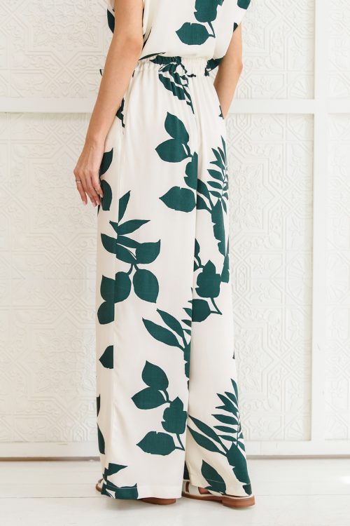 Cropped rear view of a woman wearing a matching palazzo pant and top, cream colored with green leaves print