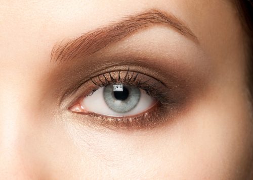 Close up of a woman with light blue eyes wearing brown eyeshadow