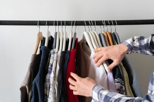 person choosing shirt on the clothes rack at home