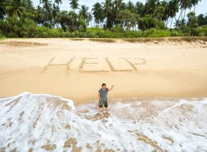 Aerial view of a man stuck on a desert island who wrote "HELP" in the sand