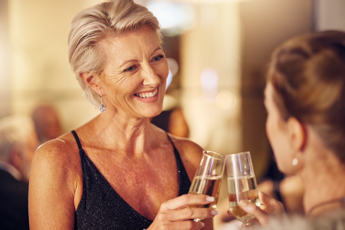 Mature woman, dressed up at a party, toasting friend with champagne