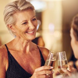 Mature woman, dressed up at a party, toasting friend with champagne