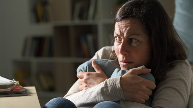 Scared middle age woman looking away at night at home