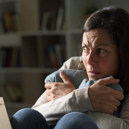 Scared middle age woman looking away at night at home