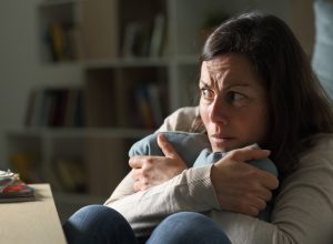 Scared middle age woman looking away at night at home
