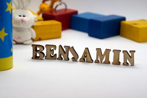 The name Benjamin spelled out in wooden cut-out letters with colorful blocks in the background