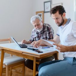 Son Giving Senior Parent Financial Advice at Home. Adult Son Doing Accounts Together With His Senior Father at Home, Planning New Purchase. Family Budget and Finances.