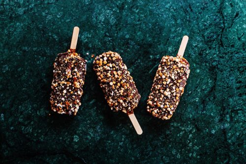 Peanut butter chocolate ice cream popsicles on dark marble table