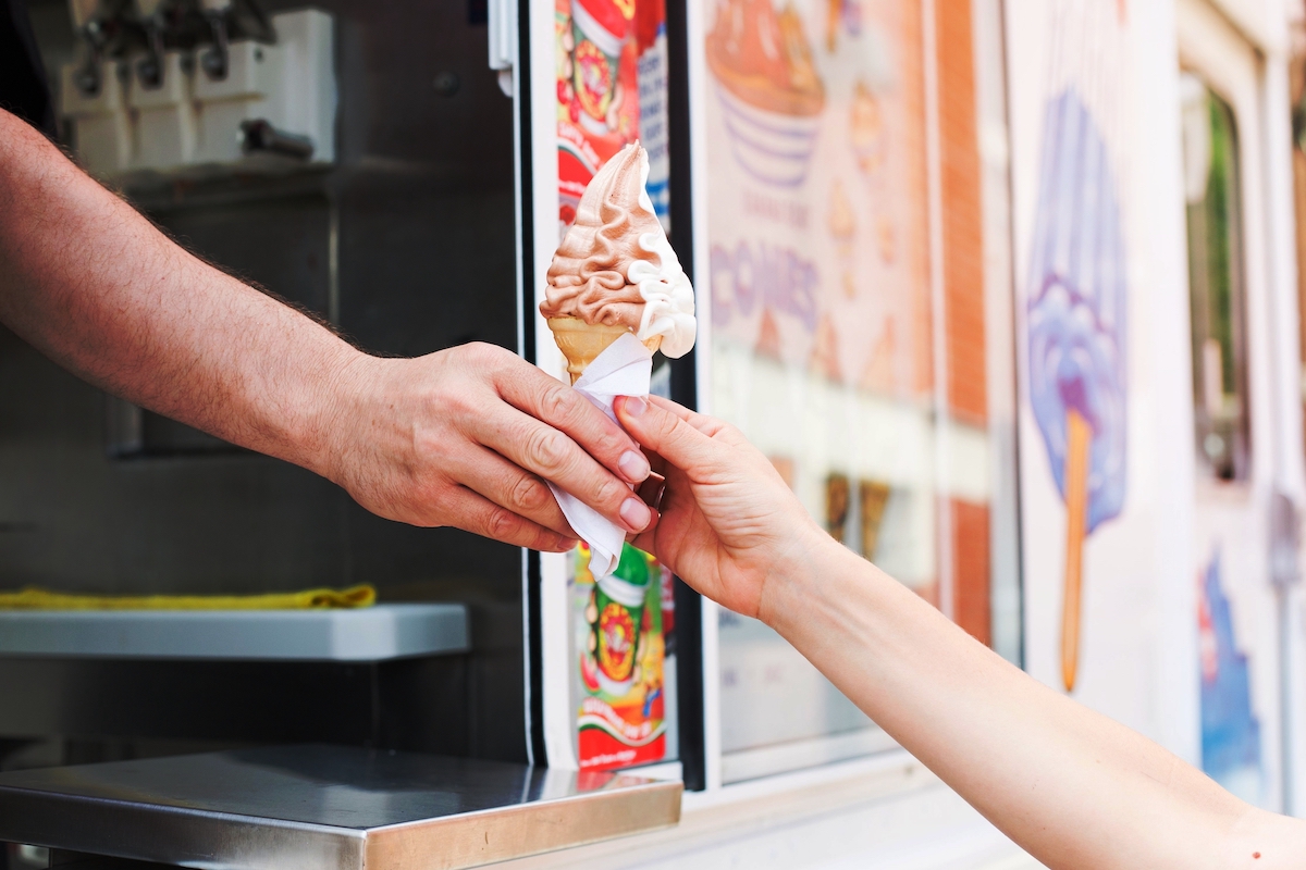 Close of up view of a person grabbing a chocolate and vanilla ice cream cone from the ice cream truck