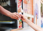 Close of up view of a person grabbing a chocolate and vanilla ice cream cone from the ice cream truck