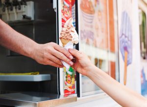 Close of up view of a person grabbing a chocolate and vanilla ice cream cone from the ice cream truck
