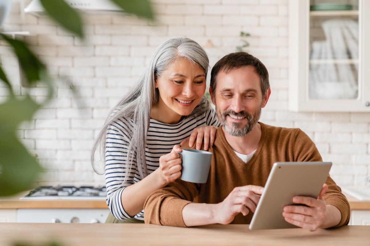 man and woman smiling and looking at ipad while asking each other questions