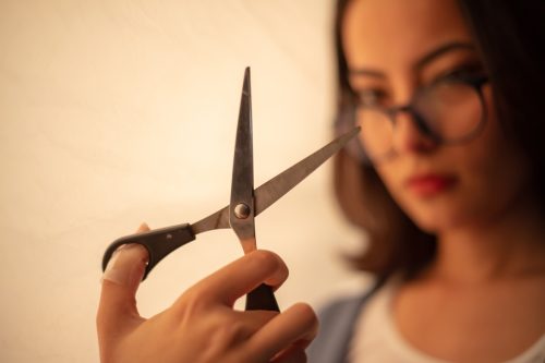 Female model is holding scissors during photo shoot in photo studio.