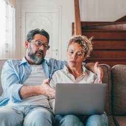 Shocked couple looking at laptop screen frustrated by unexpected bad news online. Husband and wife disappointed and feeling anxious on losing money in online lottery,