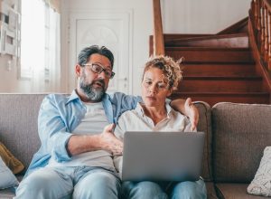 Shocked couple looking at laptop screen frustrated by unexpected bad news online. Husband and wife disappointed and feeling anxious on losing money in online lottery,