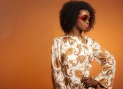 Stylish Black woman with retro outfit: big sunglasses, flared shirt, afro