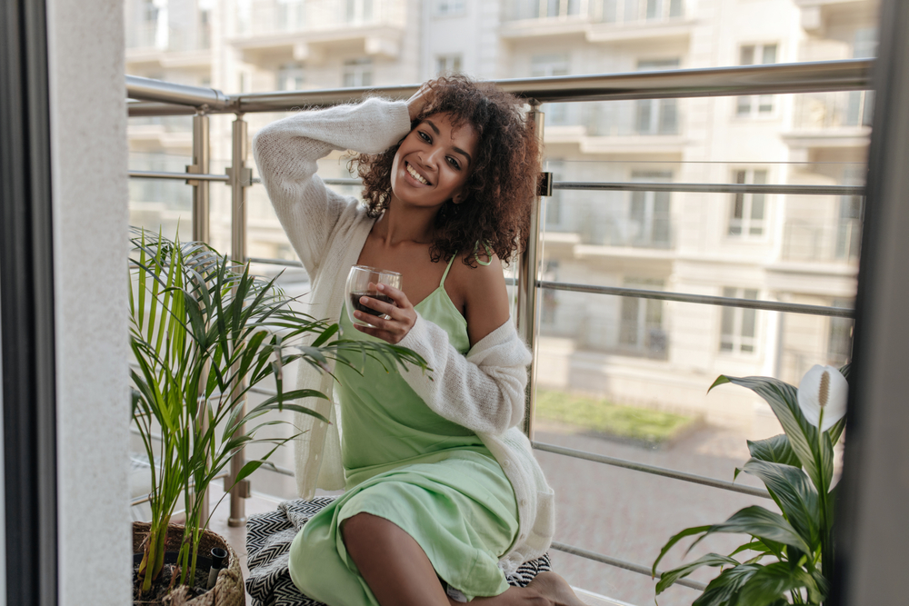 Young stylish black woman in slip dress and cardigan at home
