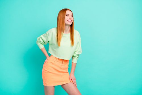 Young stylish woman in mint green top and coral miniskirt