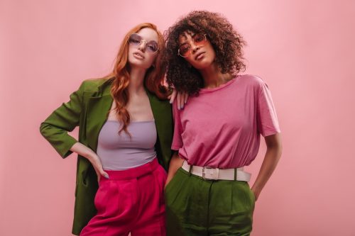 Two stylish young women in pink and green outfits