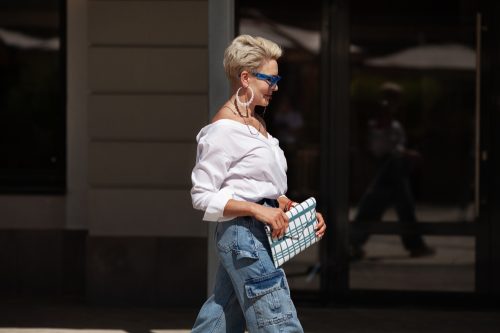 Fashionable older woman with short hair, denim cargo pants, and clutch